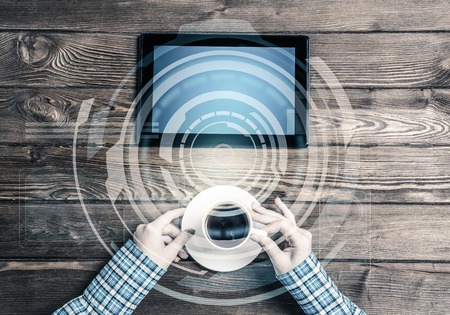 Top view of woman in checked shirt sitting at wooden table with tablet pcの写真素材