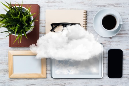 Top view of modern workplace with office stuff and cloud above presenting still office life. Mixed media.の写真素材