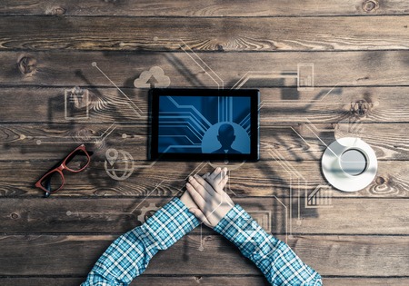Top view of woman in checked shirt sitting at table with tablet deviceの写真素材