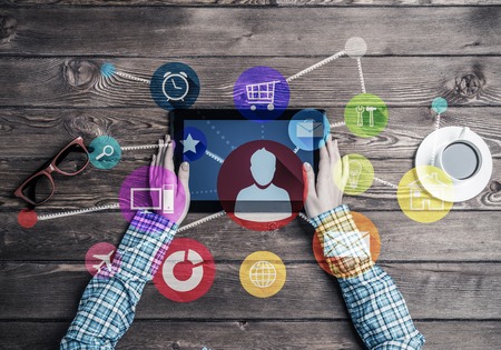 Top view of woman in checked shirt sitting at table with tablet deviceの写真素材