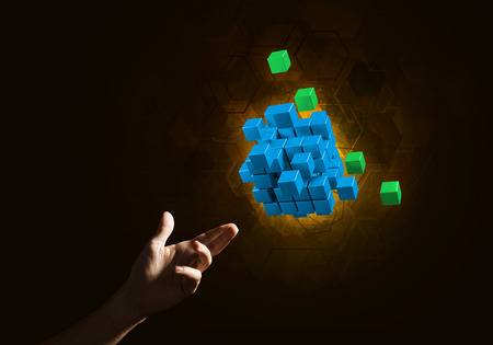 Close of man hand holding cube figure as symbol of innovation. Mixed media.の写真素材