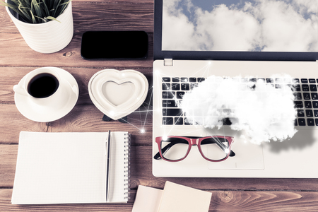 Top view of modern workplace with office stuff and cloud above presenting still office life. Mixed media.の写真素材