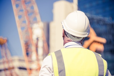 Engineer man in helmet and jacket controlling outdoor construction siteの写真素材