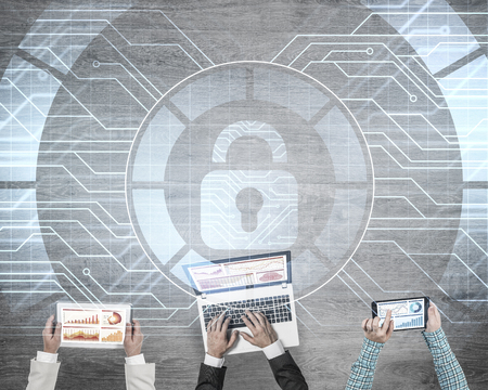 Group of people with devices in hands working together and symbol of net security and protectionの写真素材