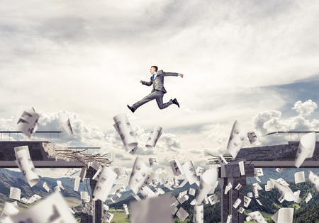 Businessman jumping over gap in bridge among flying papers as symbol of overcoming challenges. Skyscape and nature view on background. 3D rendering.の写真素材