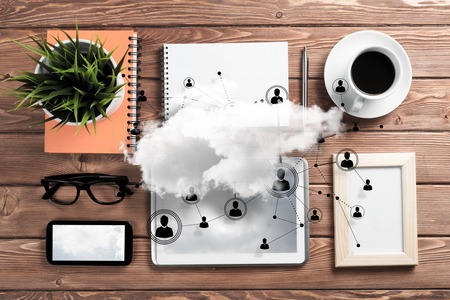Top view of modern workplace with office stuff, social network connections and clouds above as symbol of still office life. Mixed media.の写真素材