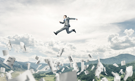 Businessman in suit running in the air among flying papers as symbol of active life position. Skyscape and nature view on background. 3D rendering.の写真素材