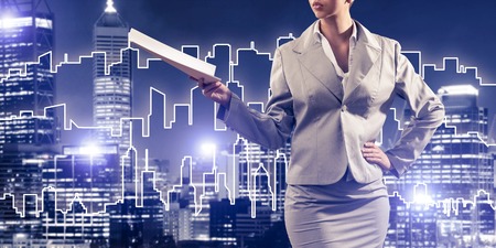 Close view of businesswoman against modern cityscape holding papers in handの写真素材
