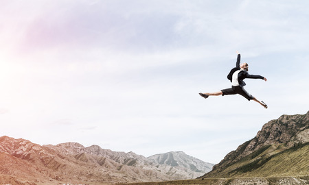 Attractive business woman in suit jumping in the air as symbol of active life position. Skyscape with sunlight and nature view on background. 3D rendering.の写真素材