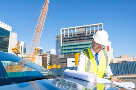 Engineer man in helmet and jacket controlling outdoor construction siteの写真素材