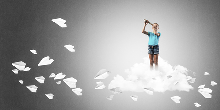 Cute kid girl standing on cloud and paper planes flying aroundの写真素材