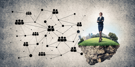 Elegant businesswoman on flying green island against concrete backgroundの写真素材
