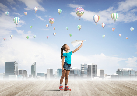 Cute kid girl standing on wooden floor and aerostats flying in airの写真素材