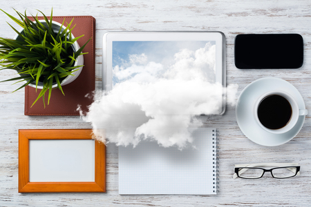 Top view of modern workplace with office stuff and cloud above presenting still office life. Mixed media.の写真素材