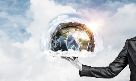 Cropped image of waitresss hand in white glove presenting Earth globe on metal tray with cloudy skyscape on background. 3D rendering. Elements of this image are furnished by NASA.の写真素材