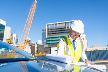 Engineer man in helmet and jacket controlling outdoor construction siteの写真素材
