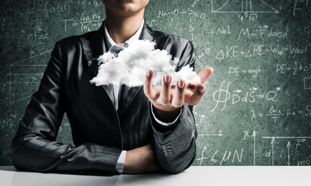 Closeup of business woman in suit presenting white cloud in her palm with business sketches on background.の写真素材