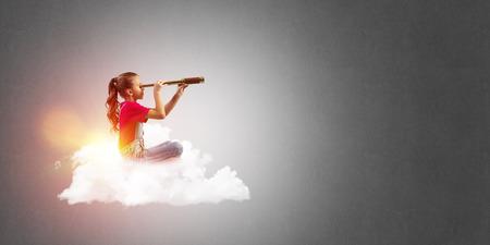 Cute kid girl on cloud looking in spyglassの写真素材