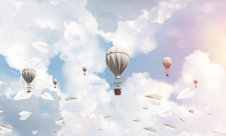 Colorful aerostats flying among paper planes and over the blue cloudy sky. 3D rendering.の写真素材