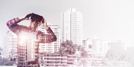 Young man with virtual reality headset or 3d glasses over cityscape backgroundの写真素材