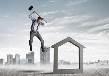 Determined businessman going to break with hammer house concrete figureの写真素材
