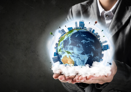 Closeup of businessman in suit keeping in hands Earth globe with buildings and flying balloons. Elements of this image are furnished by NASA.の写真素材