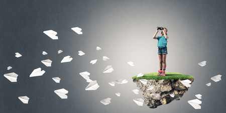 Cute kid girl sitting on floating island against concrete backgroundの写真素材