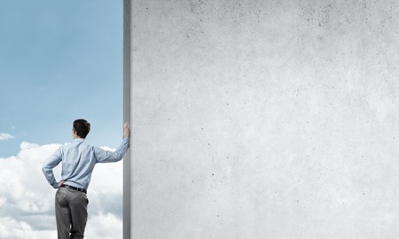 Businessman standing with back and leaning on cement blank wallの写真素材