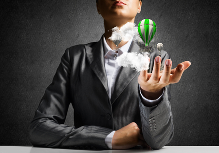 Closeup of business woman in suit presenting flying aerostate among clouds in her palm with dark wall on background. 3D rendering.の写真素材