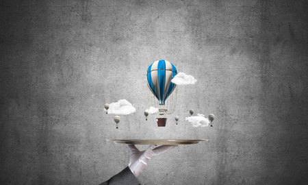 Closeup of waitresss hand in glove presenting flying aerostats on metal tray with gray concrete wall on background. 3D rendering.の写真素材