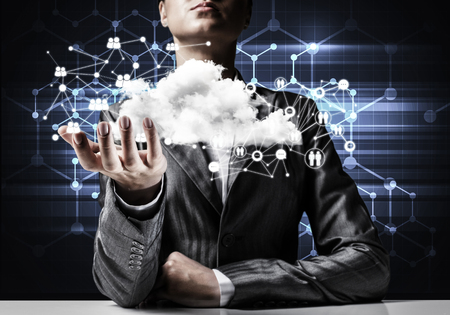 Businessman in suit keeping cloud with network connections in hand and network systems on background.の写真素材