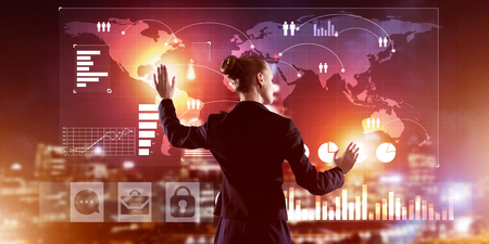 Back view of businesswoman working with virtual panel and night city at backgroundの写真素材