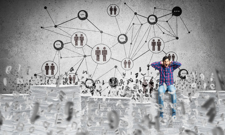 Young man in casual wear sitting on pile of documents among flying letters with social network structure on background. Mixed media.の写真素材