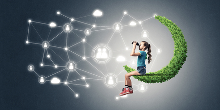Cute kid girl sitting on green moon and social connection conceptの写真素材