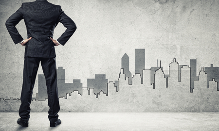 Back view of businessman and sketches of construction project on wallの写真素材