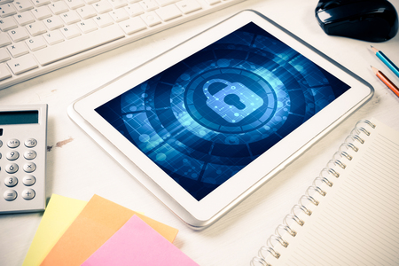 Business workplace with office stuff and tablet with padlock icon on screenの写真素材