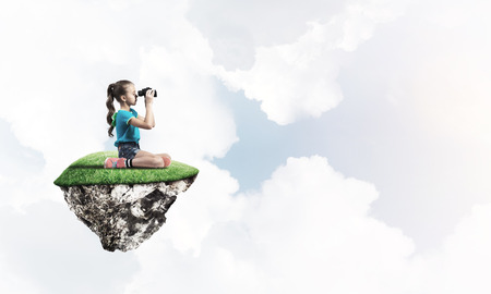 Cute smiling girl sitting on floating island high in skyの写真素材