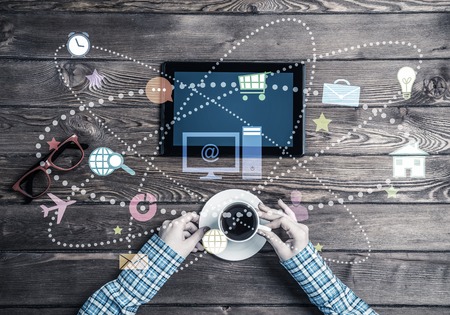 Top view of woman in checked shirt sitting at table with tablet deviceの写真素材