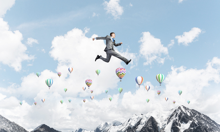 Businessman in suit running in the air as symbol of active life position. Skyscape with flying balloons and nature view on background. 3D rendering.の写真素材