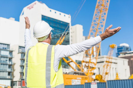Engineer man in helmet and jacket controlling outdoor construction siteの写真素材