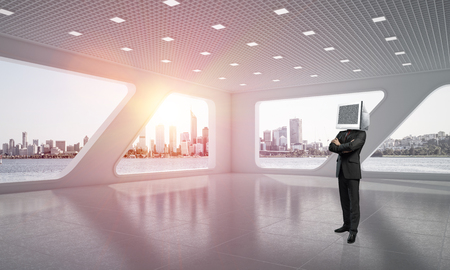 Businessman in suit with monitor instead of head keeping arms crossed while standing inside office building. 3D rendering.の写真素材