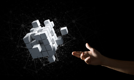 Close of man hand holding cube figure as symbol of innovation. Mixed media.の写真素材