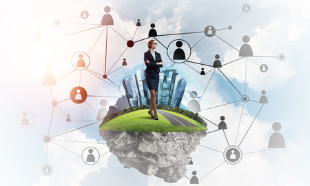 Elegant businesswoman on flying green island floating in blue skyの写真素材