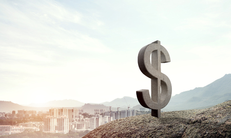 Stone dollar symbol outdoors on green hill as currency signの写真素材