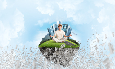 Man in white clothing keeping eyes closed and looking concentrated while meditating on island in the air among flying letters with cloudy skyscape on background. 3D rendering.の写真素材