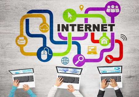 Group of three people with devices in hands working together as symbol of networking and communicationの写真素材