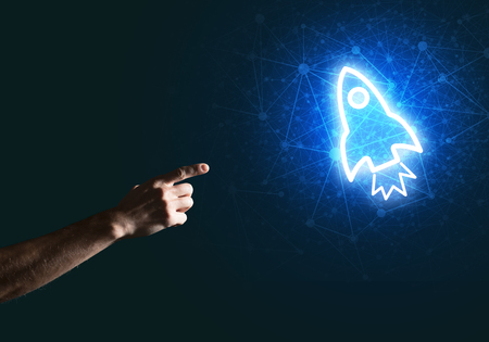 Rocket glowing icon and man hand on dark backgroundの写真素材
