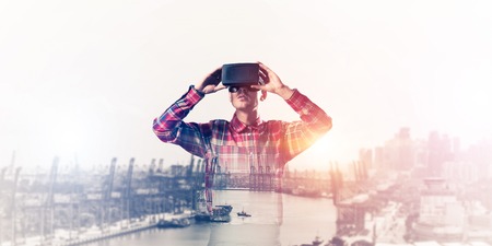 Young man with virtual reality headset or 3d glasses over cityscape backgroundの写真素材