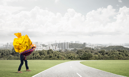 Builder man carrying paper ball on his backの写真素材