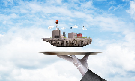 Cropped image of waitresss hand in white glove presenting modern city block on metal tray with blue...
